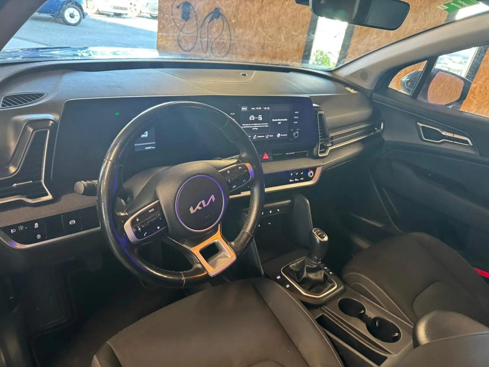 Vue intérieure côté conducteur du Kia Sportage noir 2022, volant cuir, tableau de bord numérique et boîte manuelle.