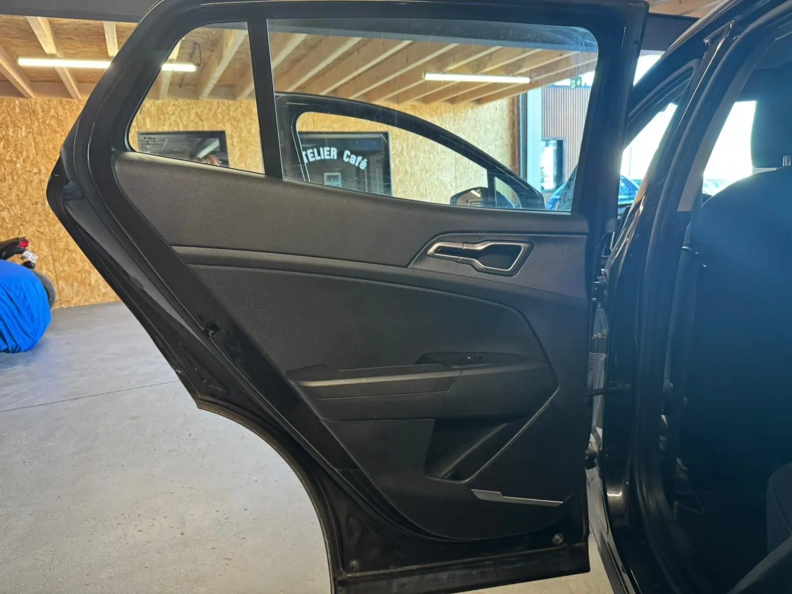 Vue intérieure de la porte arrière gauche noire du Kia Sportage 2022, mettant en valeur sa garniture sobre et moderne.