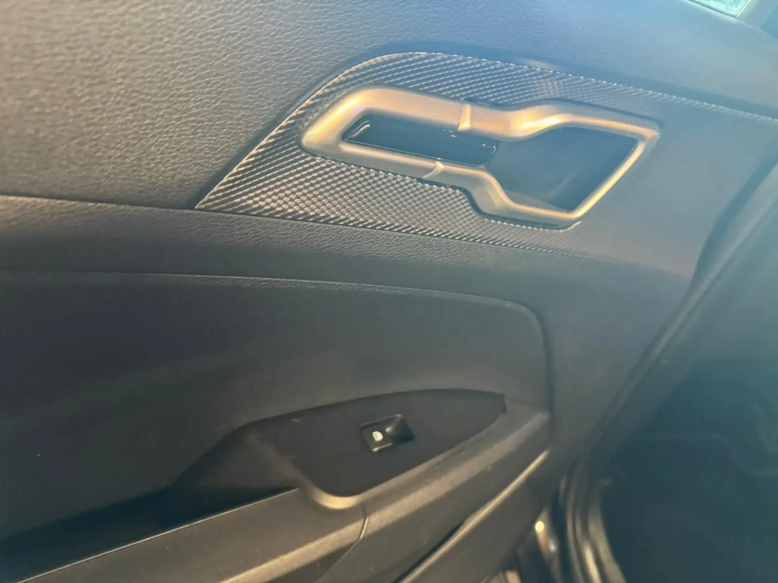 Poignée intérieure et commande de lève-vitre côté droit de la porte noire du Kia Sportage 2022 diesel hybride.