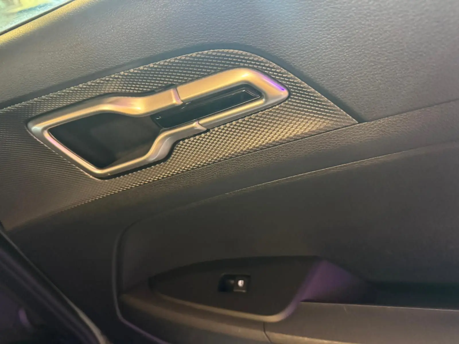 Poignée intérieure arrière droite en métal brossé sur porte noire du Kia Sportage 2022 diesel hybride.