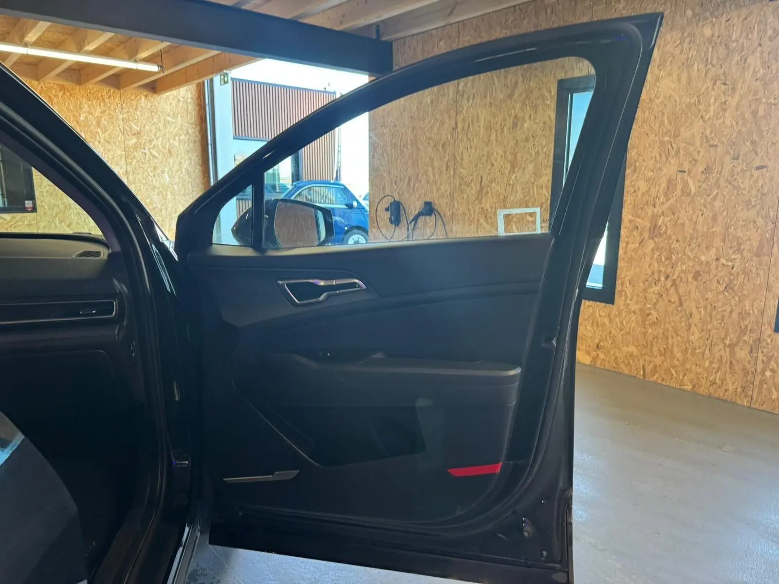 Vue intérieure de la porte avant gauche noire du Kia Sportage 2022, avec garniture sombre et poignée argentée.