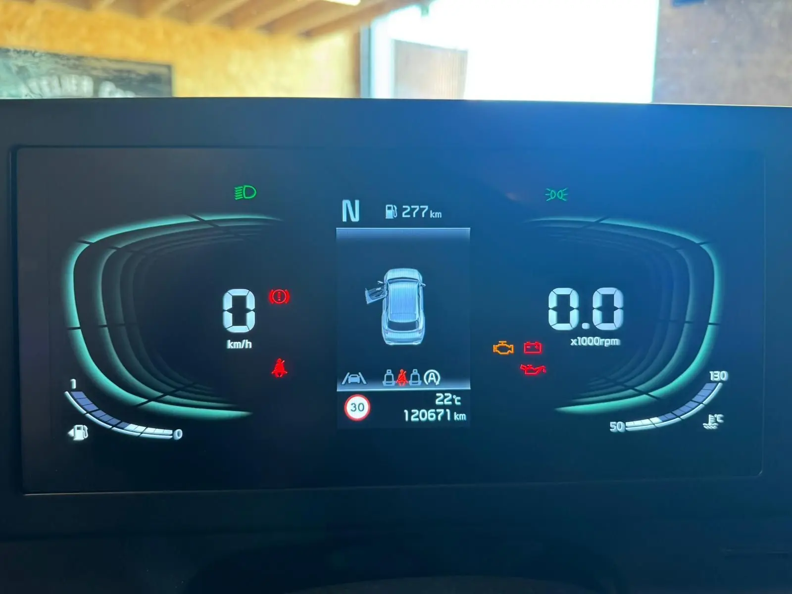 Tableau de bord numérique du Kia Sportage noir 2022, affichant vitesse, régime, autonomie et alertes moteur.