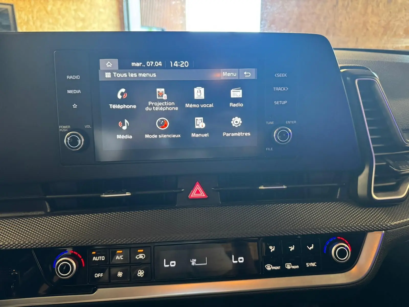 Vue rapprochée de l’écran tactile et de la console centrale du Kia Sportage noir, affichant les commandes multimédia et climatisation.