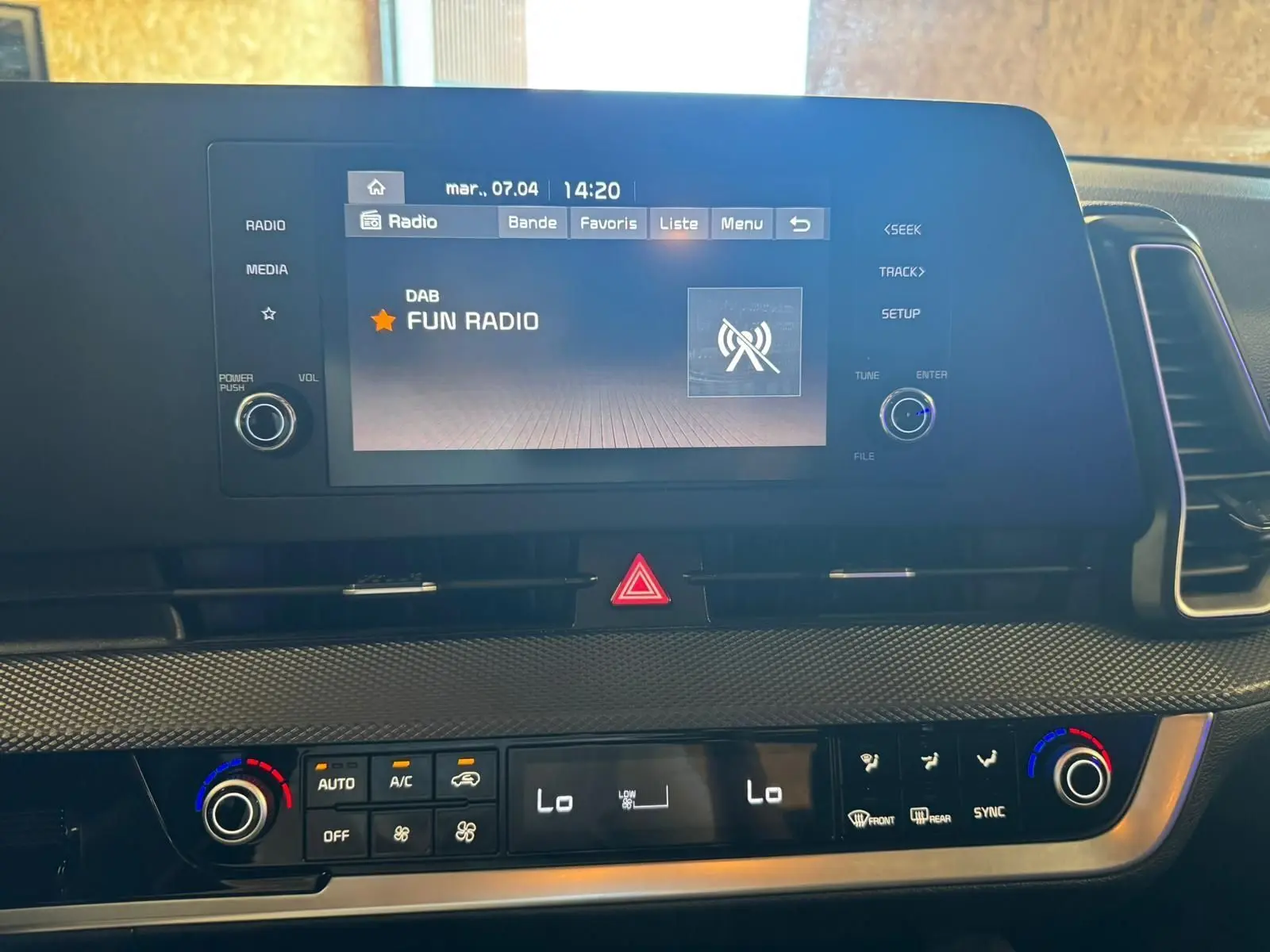Vue rapprochée de l’écran multimédia et de la console de climatisation du Kia Sportage noir, affichant Fun Radio.