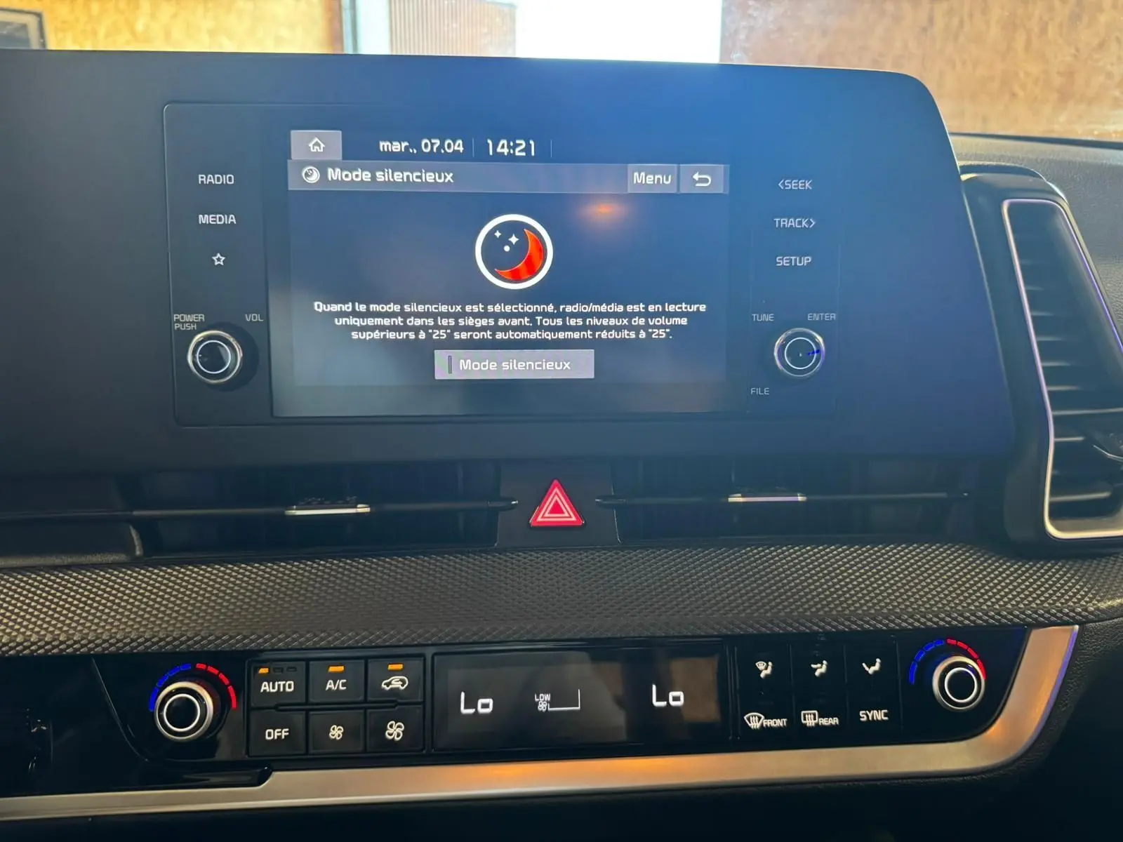 Vue rapprochée du tableau de bord noir du Kia Sportage 2022, avec écran tactile affichant le mode silencieux et commandes climatisation.