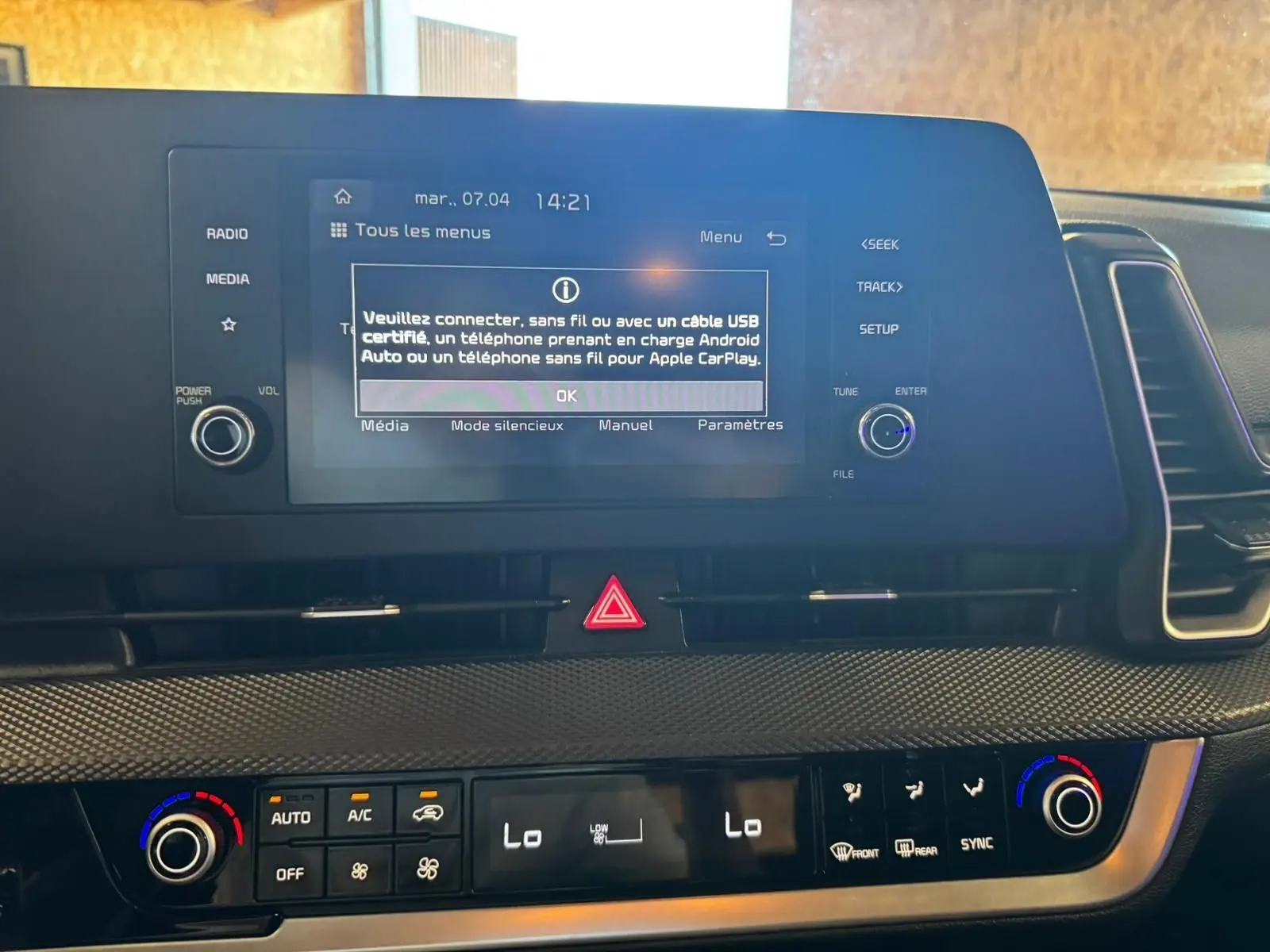 Gros plan sur l’écran central et la console de climatisation du Kia Sportage noir, affichant les réglages multimédia et température.