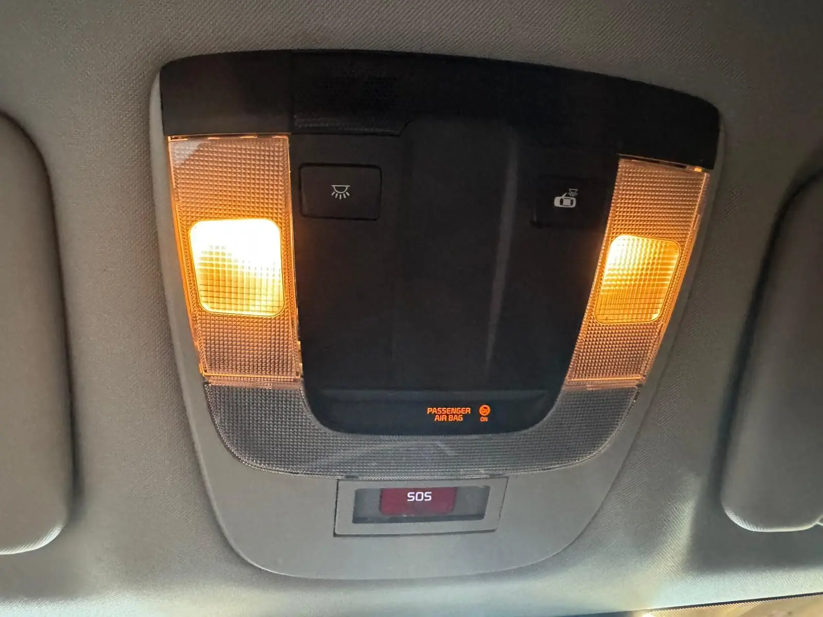 Plafonnier intérieur allumé avec boutons de commande et affichage SOS dans un Kia Sportage noir, vue de dessous.