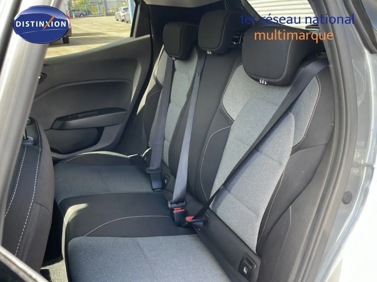 Vue intérieure arrière droite de la Renault Clio 2025, montrant les sièges tissu gris clair et noir avec ceinture de sécurité.