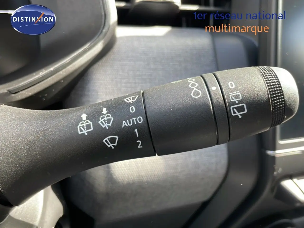 Gros plan sur la commande des essuie-glaces d’une Renault Clio 2025, intérieur noir avec détails fonctionnels blancs.