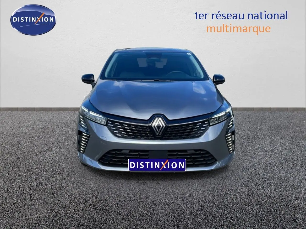 Renault Clio gris schiste métal vue de face, avec calandre et feux LED distinctifs allumés.