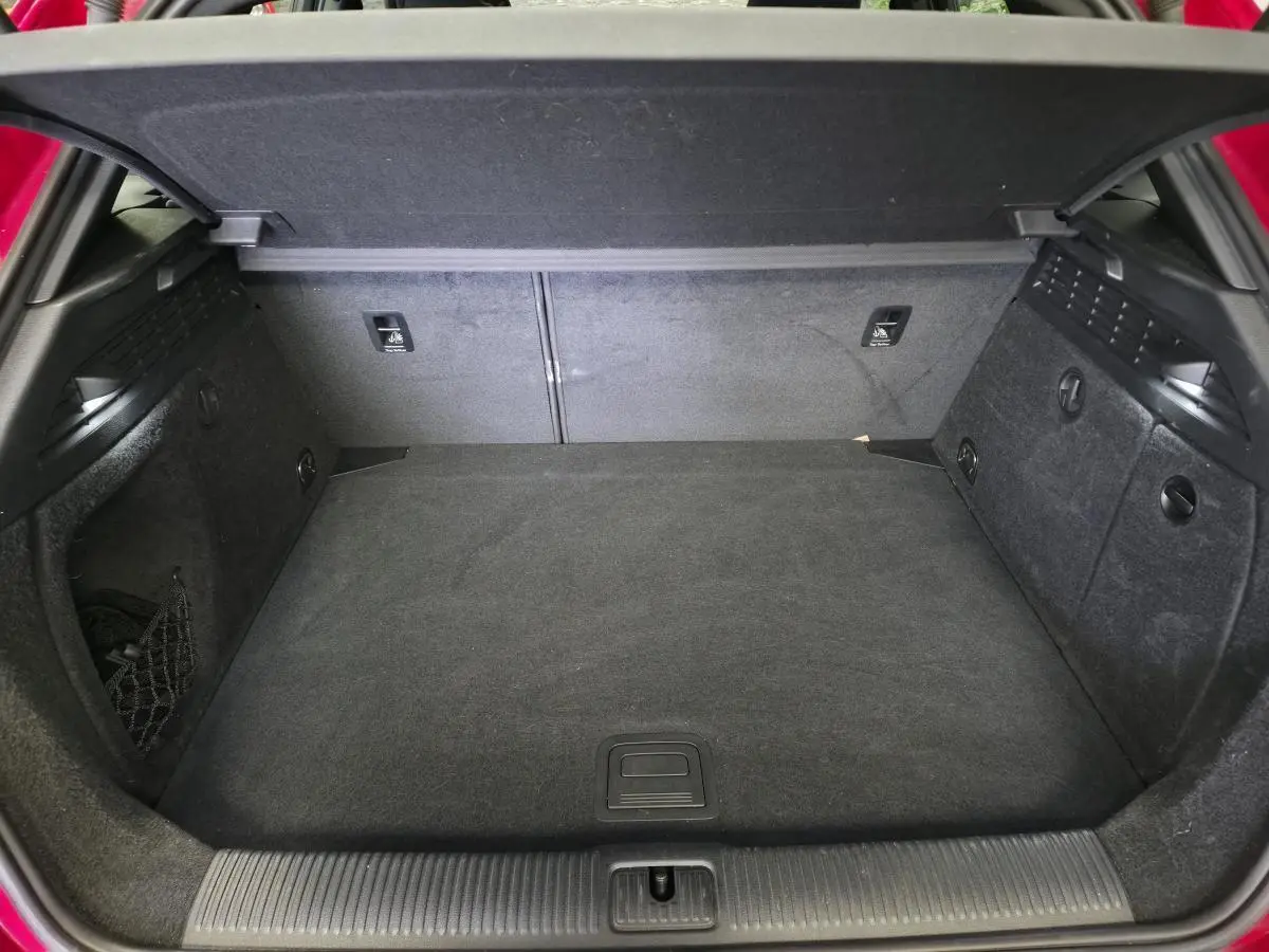 Coffre ouvert de l'Audi A3 Sportback rouge, montrant l'espace de chargement et la moquette noire.