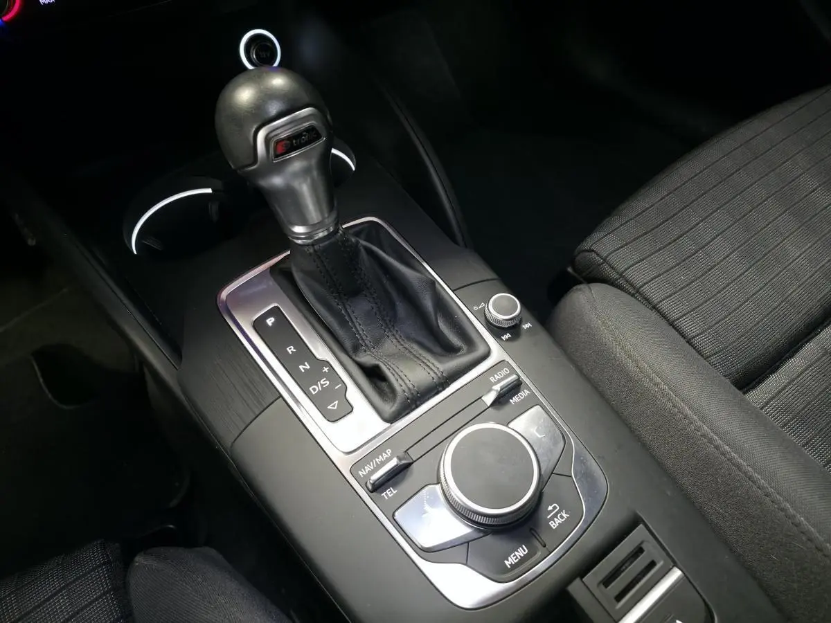 Gros plan sur la console centrale noire de l'Audi A3 Sportback avec levier de vitesse S tronic et commandes multimédia.