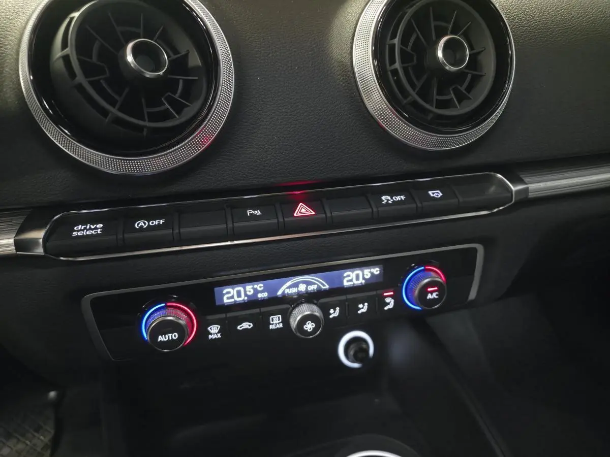 Détail du tableau de bord noir de l'Audi A3 Sportback 2019 avec commandes climatisation bi-zone et aérateurs ronds chromés.