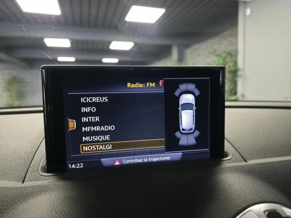 Écran central de l’Audi A3 Sportback 2019 affichant la sélection radio FM avec vue du véhicule en mode stationnement.