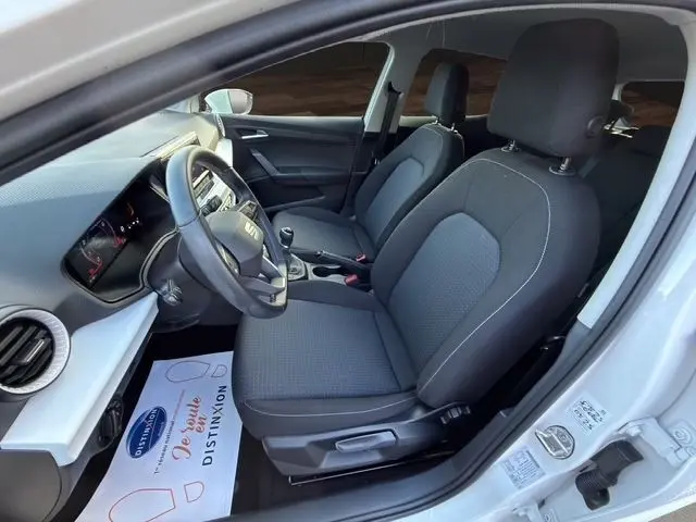 Vue intérieure côté conducteur de la SEAT Ibiza blanche 2023, volant cuir multifonctions et sièges tissu gris.