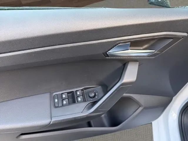 Vue rapprochée de la porte avant gauche blanche de la SEAT IBIZA 2023, avec commandes électriques des vitres et poignée argentée.