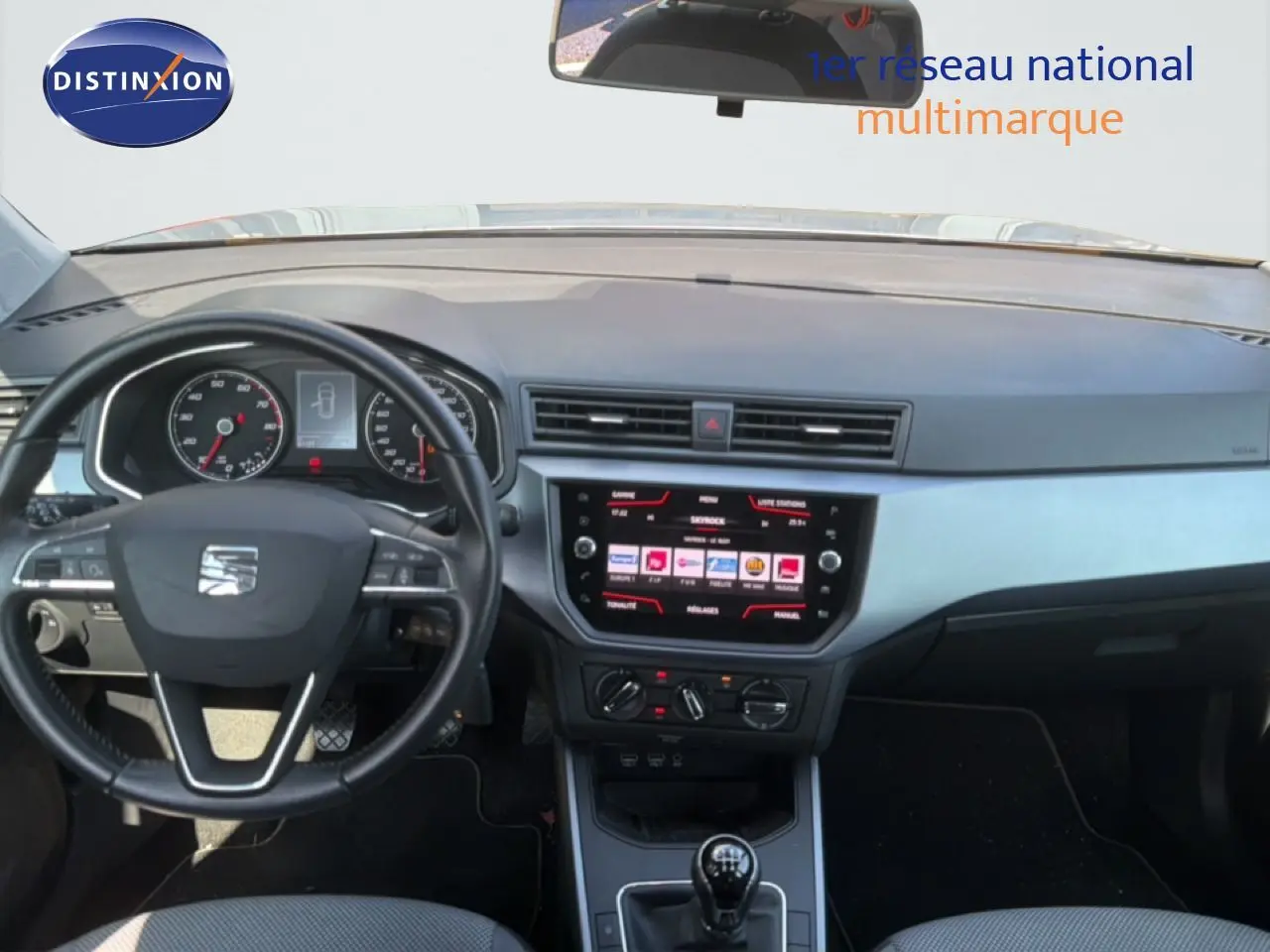 Vue intérieure frontale du tableau de bord et volant noir d'une SEAT Arona 2018 avec écran tactile et commandes manuelles.