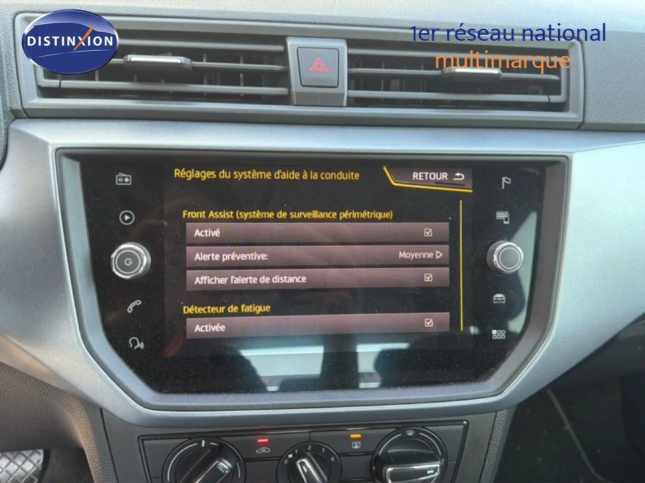 Vue rapprochée de l’écran tactile central du tableau de bord du SEAT Arona gris urbain avec toit noir, affichant les réglages d’aide à la conduite.