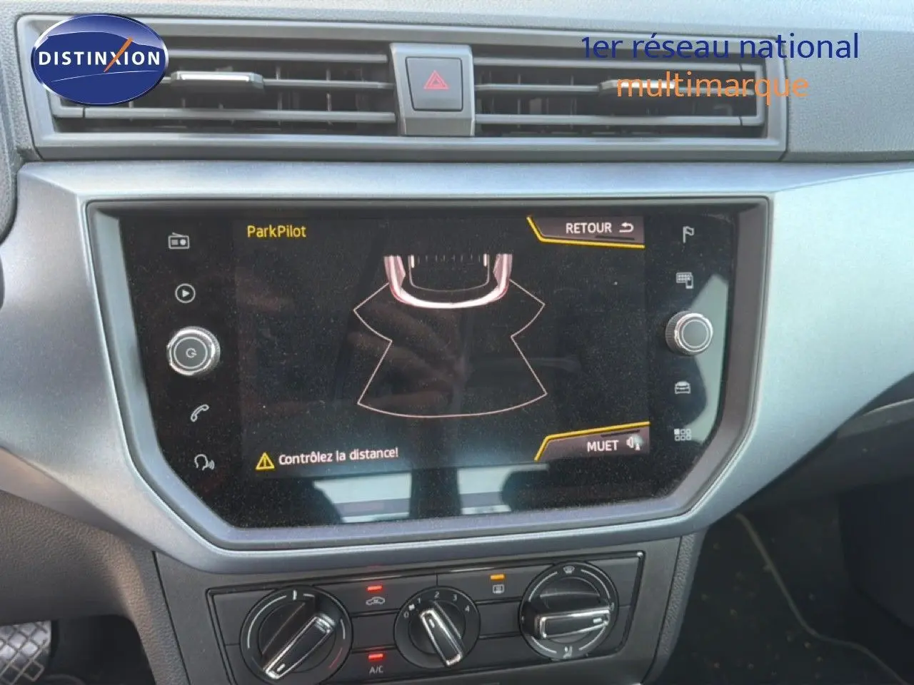 Vue rapprochée de l’écran tactile central du tableau de bord d’un SEAT Arona gris urbain avec toit noir, affichant l’aide au stationnement ParkPilot.