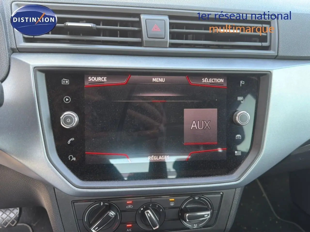 Vue rapprochée de l’écran tactile central du tableau de bord du SEAT Arona gris urbain avec toit noir, affichant le menu AUX.