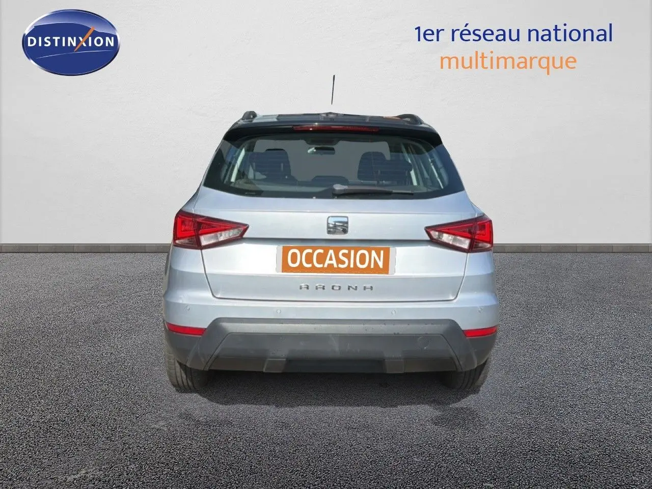 Vue arrière d'un SEAT Arona gris urbain avec toit noir, immatriculé occasion, en extérieur sur sol goudronné.