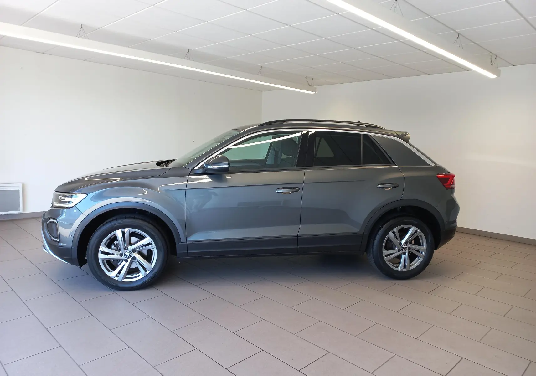 Volkswagen T-Roc 2025 gris Indium en profil droit, jantes alliage 17’’ Valencia et pneus avec écrous antivol.