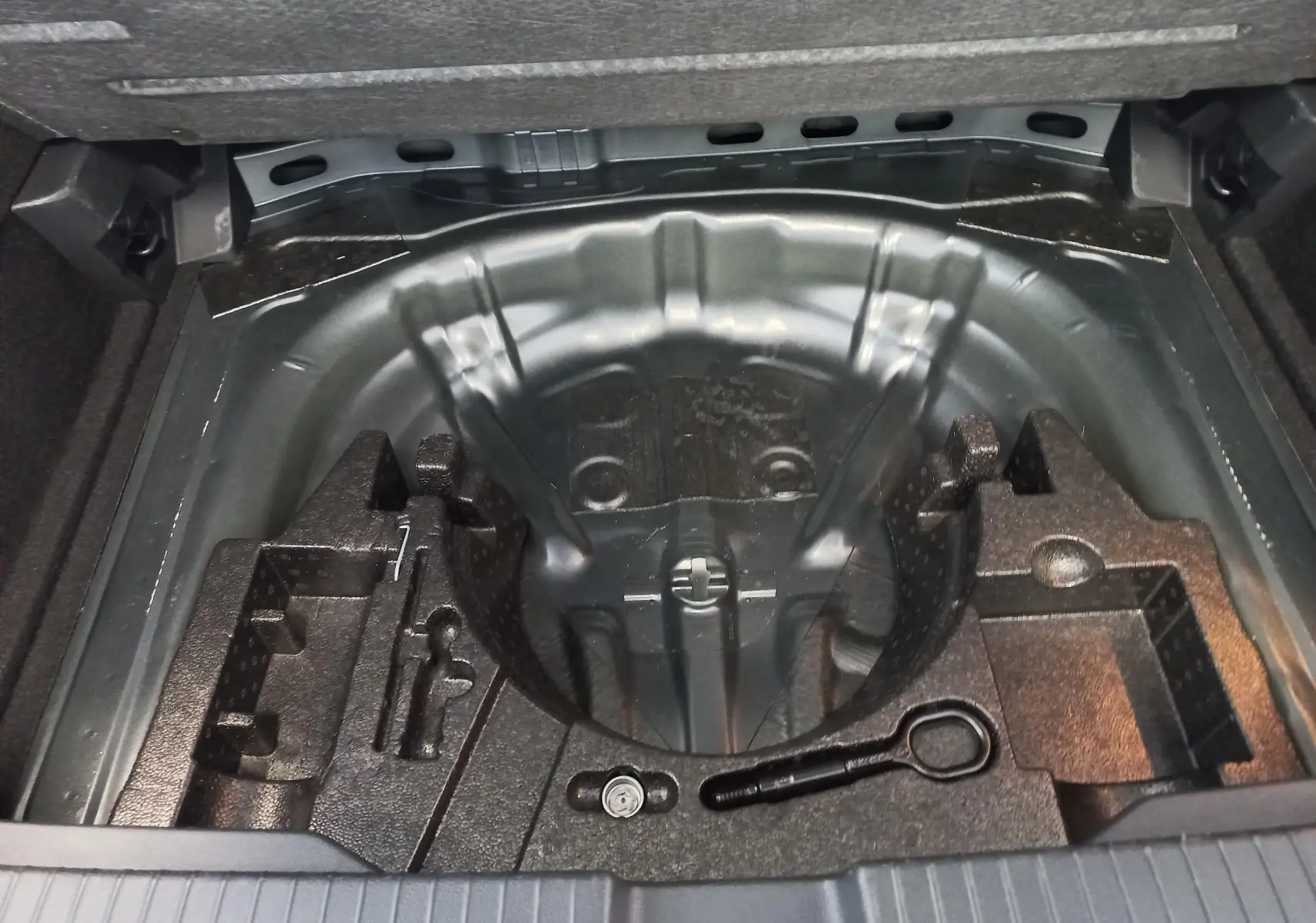 Coffre ouvert du Volkswagen T-Roc 2025 montrant le rangement sous plancher sans roue de secours.
