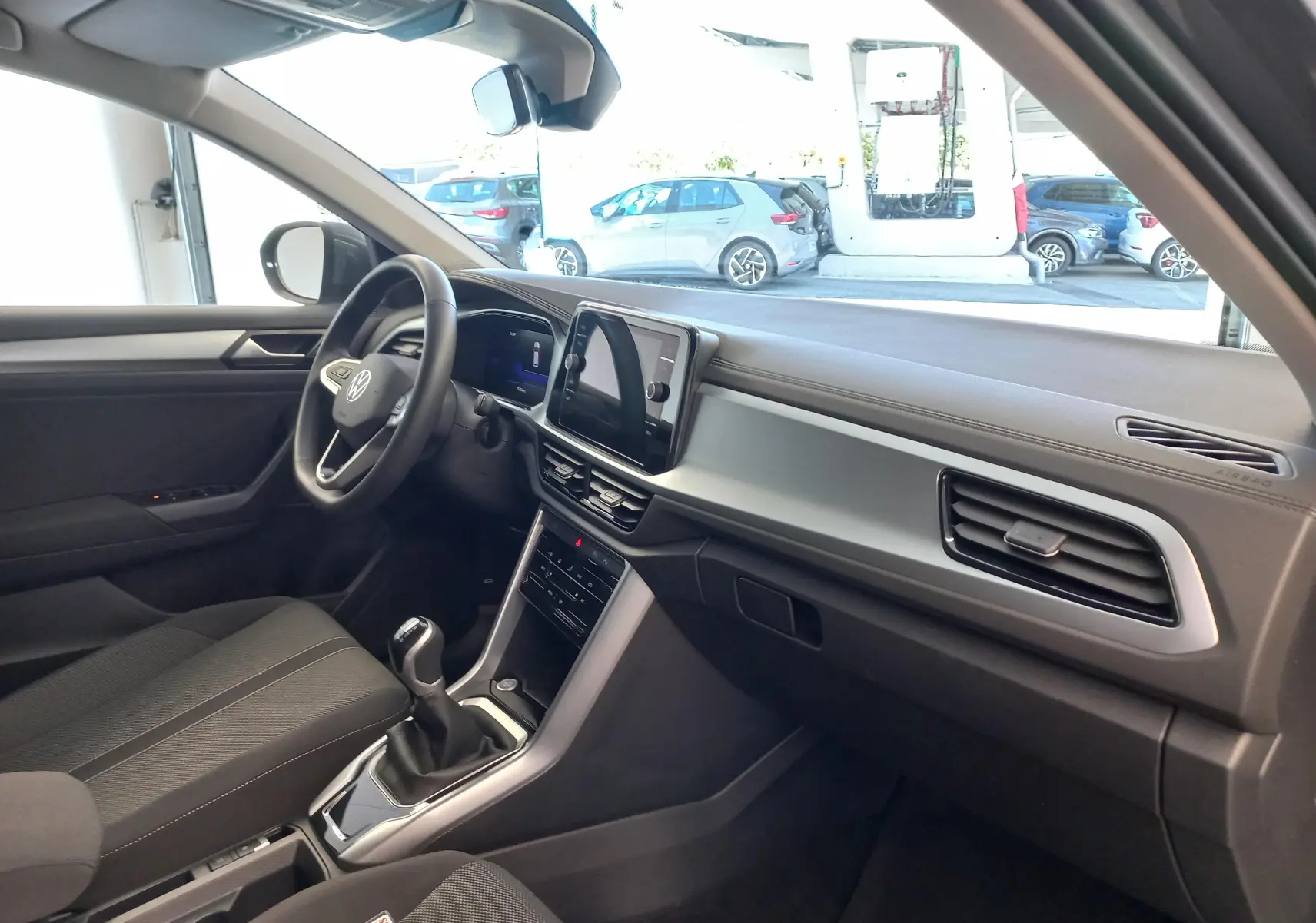 Vue intérieure côté conducteur du Volkswagen T-Roc 2025, mettant en valeur le tableau de bord moderne et la boîte manuelle.