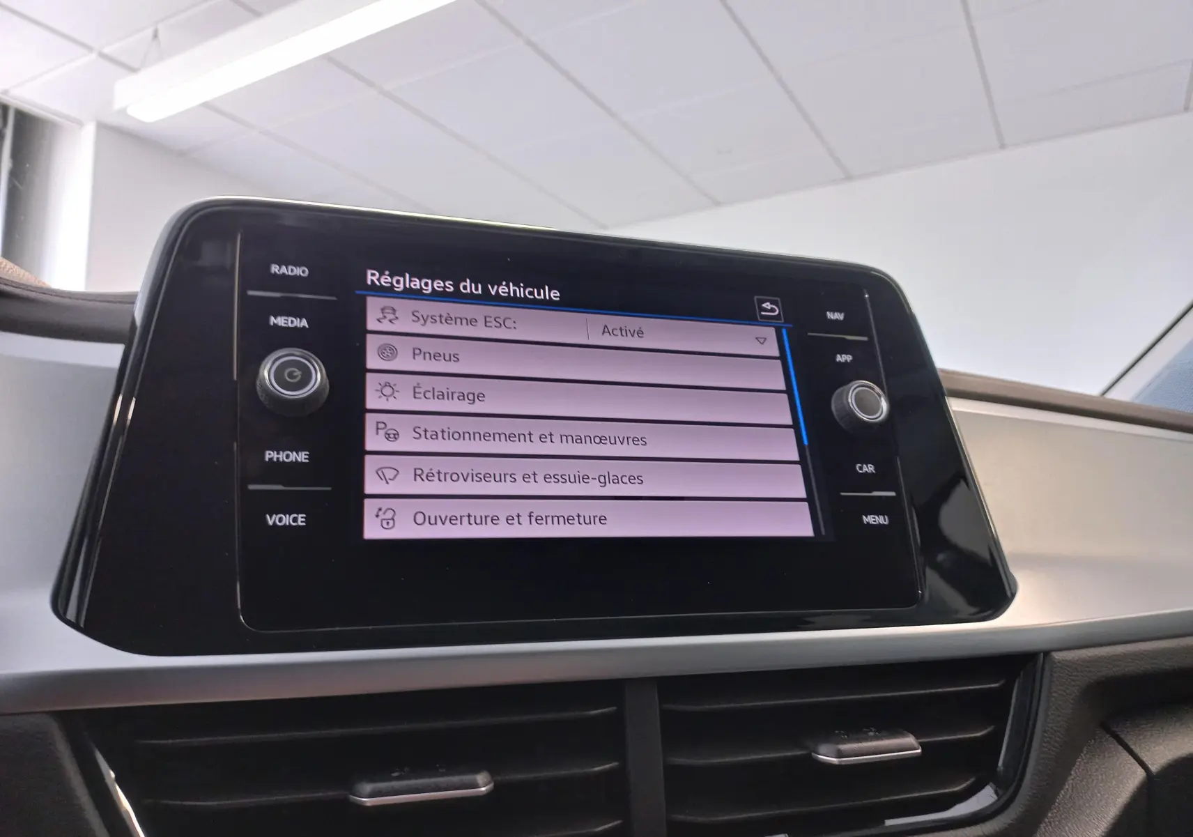 Écran tactile central du Volkswagen T-Roc 2025 affichant les réglages du véhicule dans un intérieur clair.