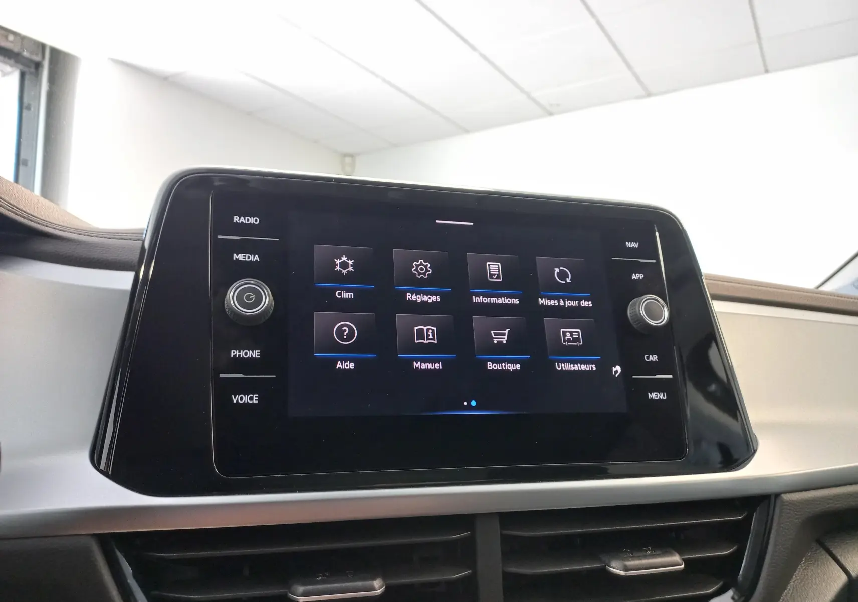 Écran tactile central du Volkswagen T-Roc 2025 affichant le menu principal avec commandes physiques sur les côtés.
