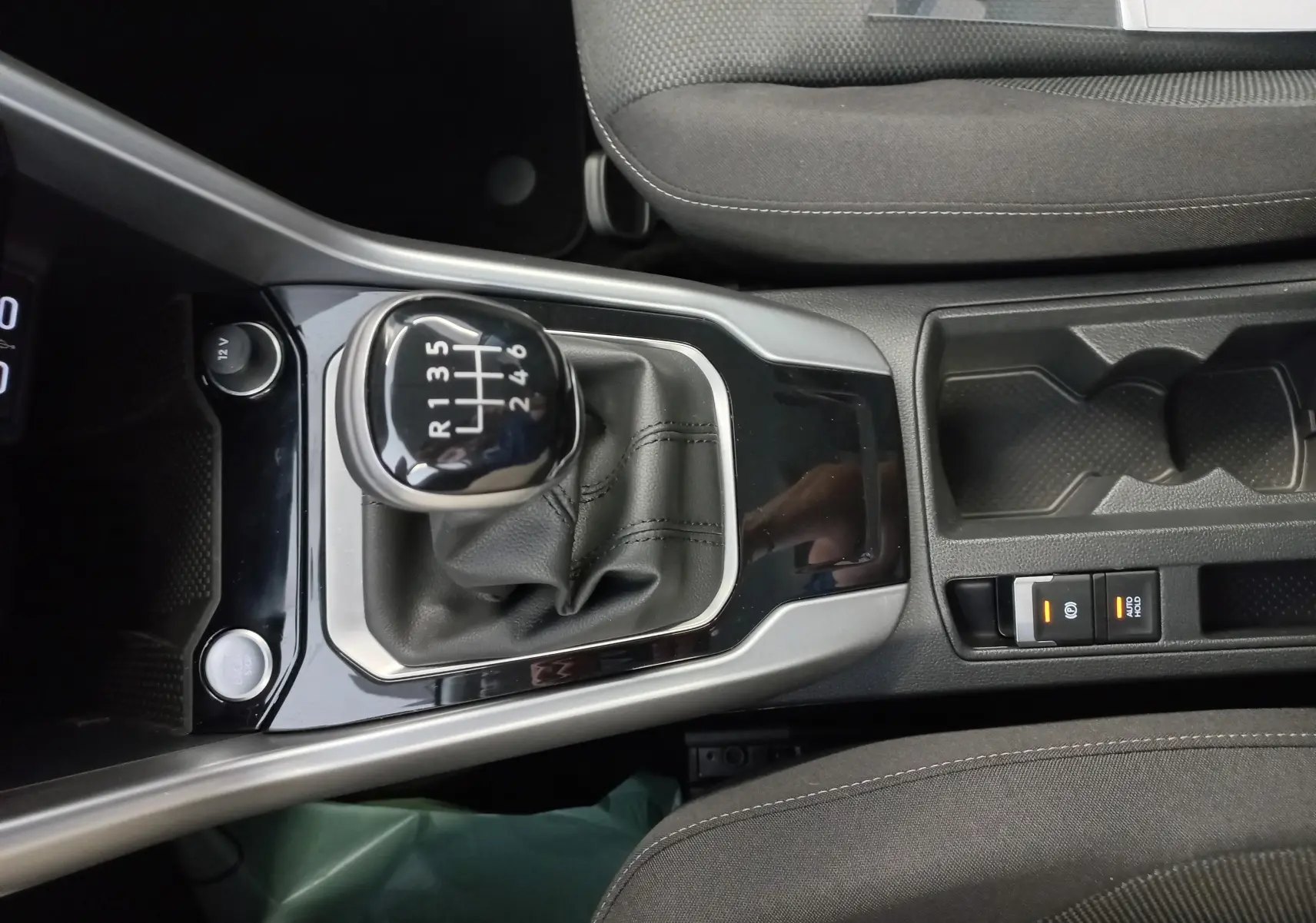 Gros plan intérieur sur la console centrale du Volkswagen T-Roc 2025, mettant en valeur le levier de vitesses manuel et les sièges gris.