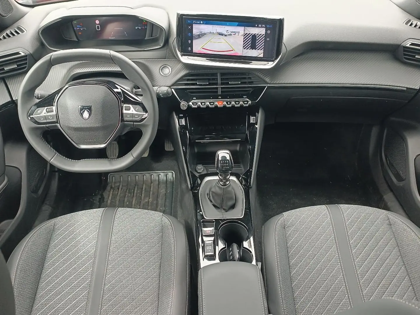 Vue intérieure frontale du poste de conduite du Peugeot 2008 1.2 100 allure, avec volant compact, écran tactile et levier de vitesses manuel.