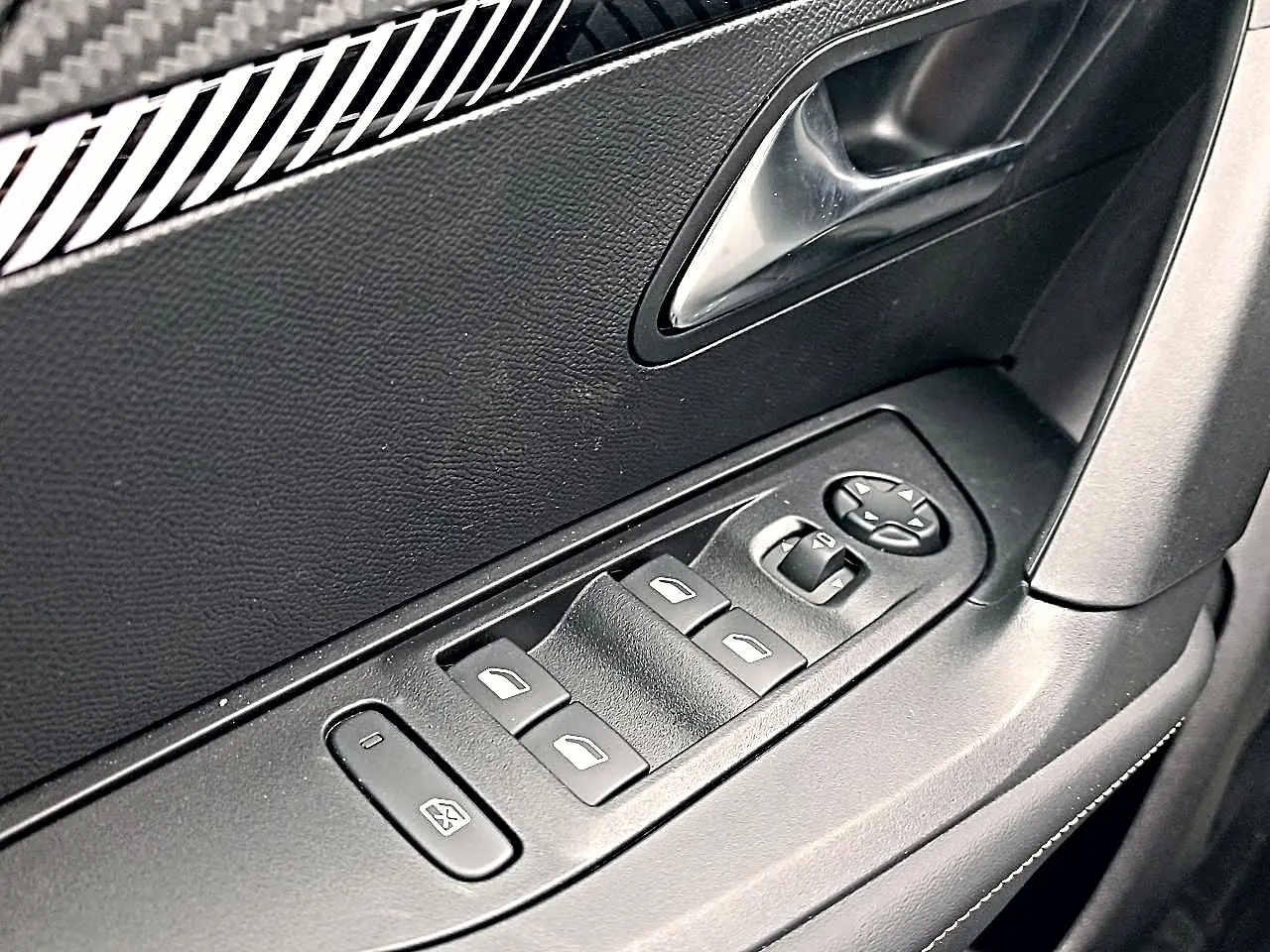 Gros plan sur les commandes de vitres électriques et rétroviseurs sur la porte côté conducteur d'une Peugeot 2008.