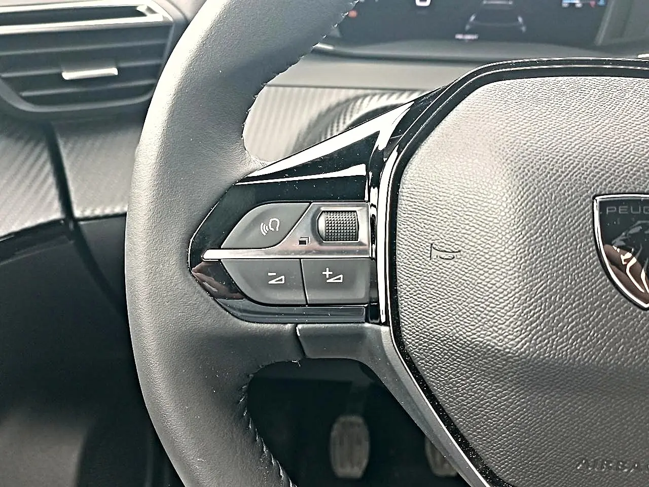 Gros plan sur le volant multifonction noir de la Peugeot 2008 1.2 100 allure avec commandes audio intégrées.