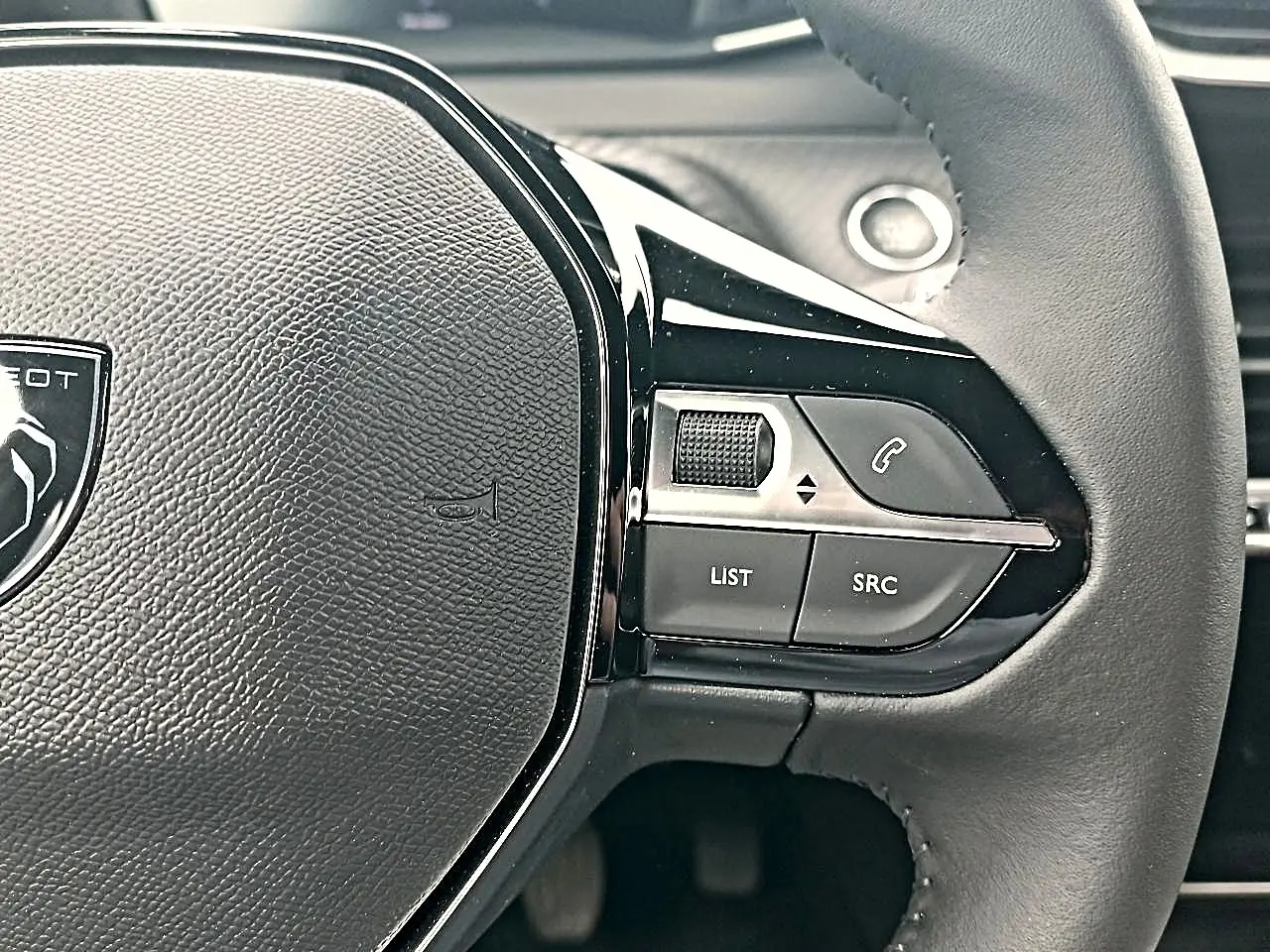 Gros plan sur le volant noir du Peugeot 2008 1.2 100 allure avec commandes multifonctions côté droit.