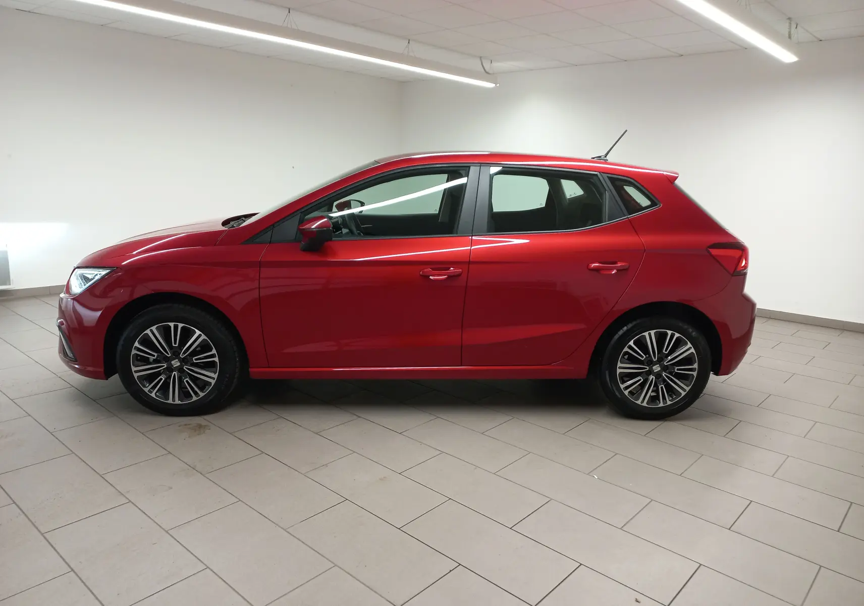 SEAT Ibiza 2025 Rouge Désir vue de profil côté gauche, avec jantes alliage et lignes dynamiques marquées.