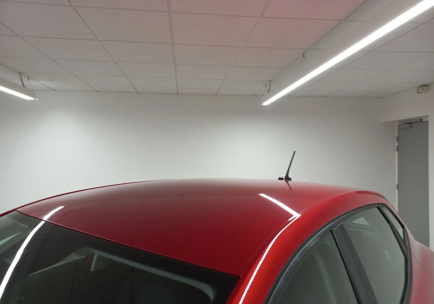 Toit et partie arrière droite d'une SEAT Ibiza 2025 rouge désir, avec antenne courte, vue en intérieur.