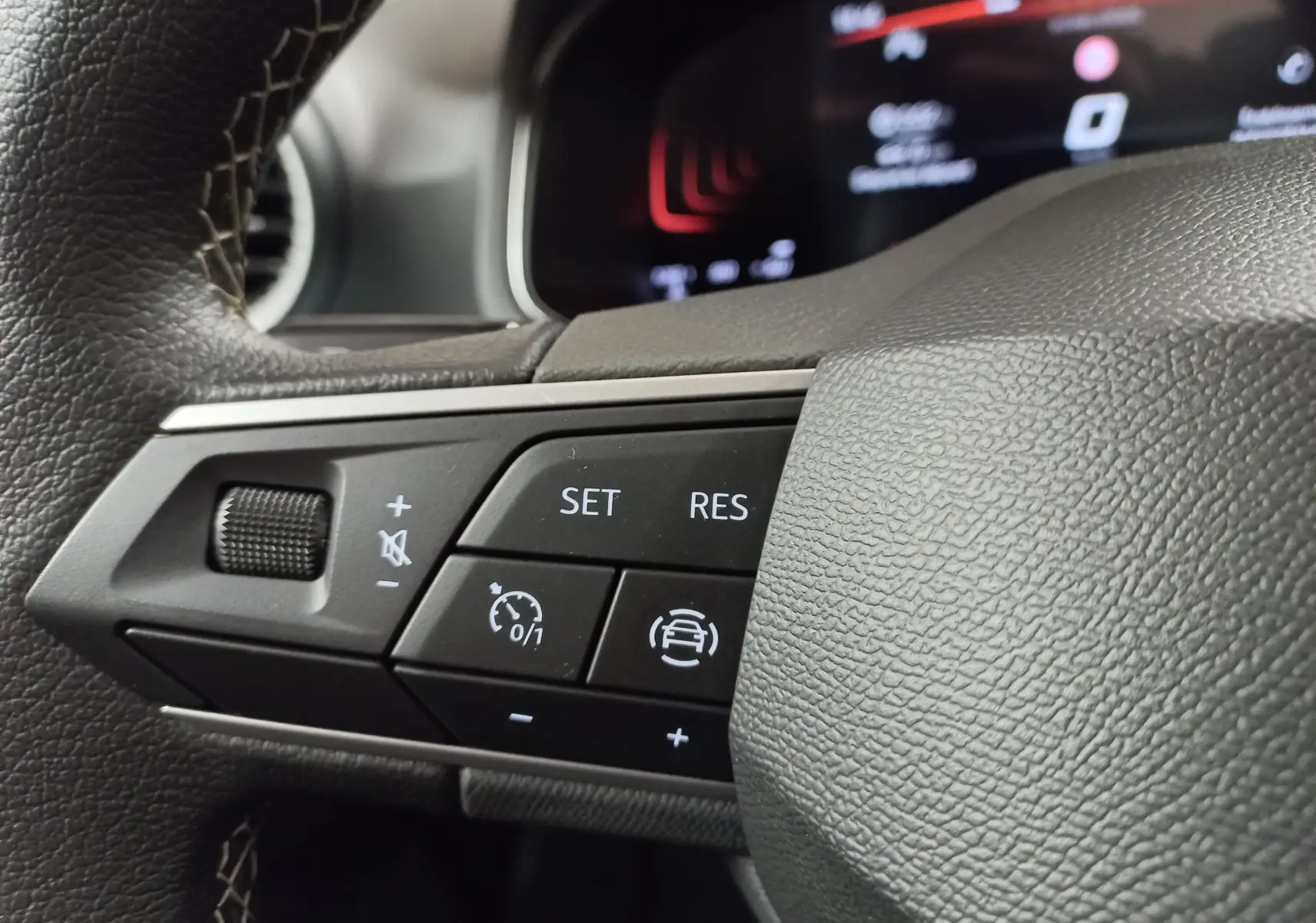 Gros plan sur les commandes au volant gauche de la SEAT Ibiza 2025, avec boutons de régulateur et assistance au maintien de voie.