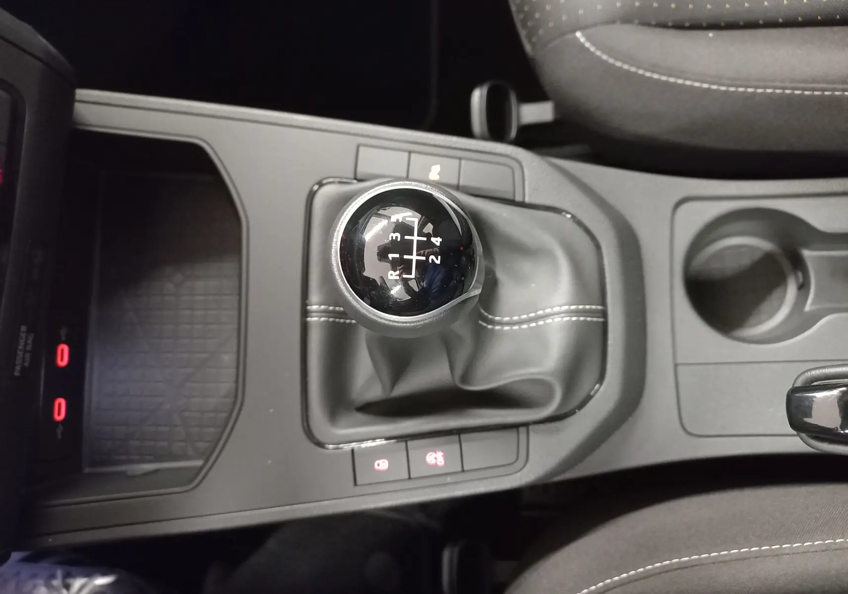 Vue plongeante sur le levier de vitesses manuel de la SEAT IBIZA 2025, avec coutures blanches sur soufflet noir.