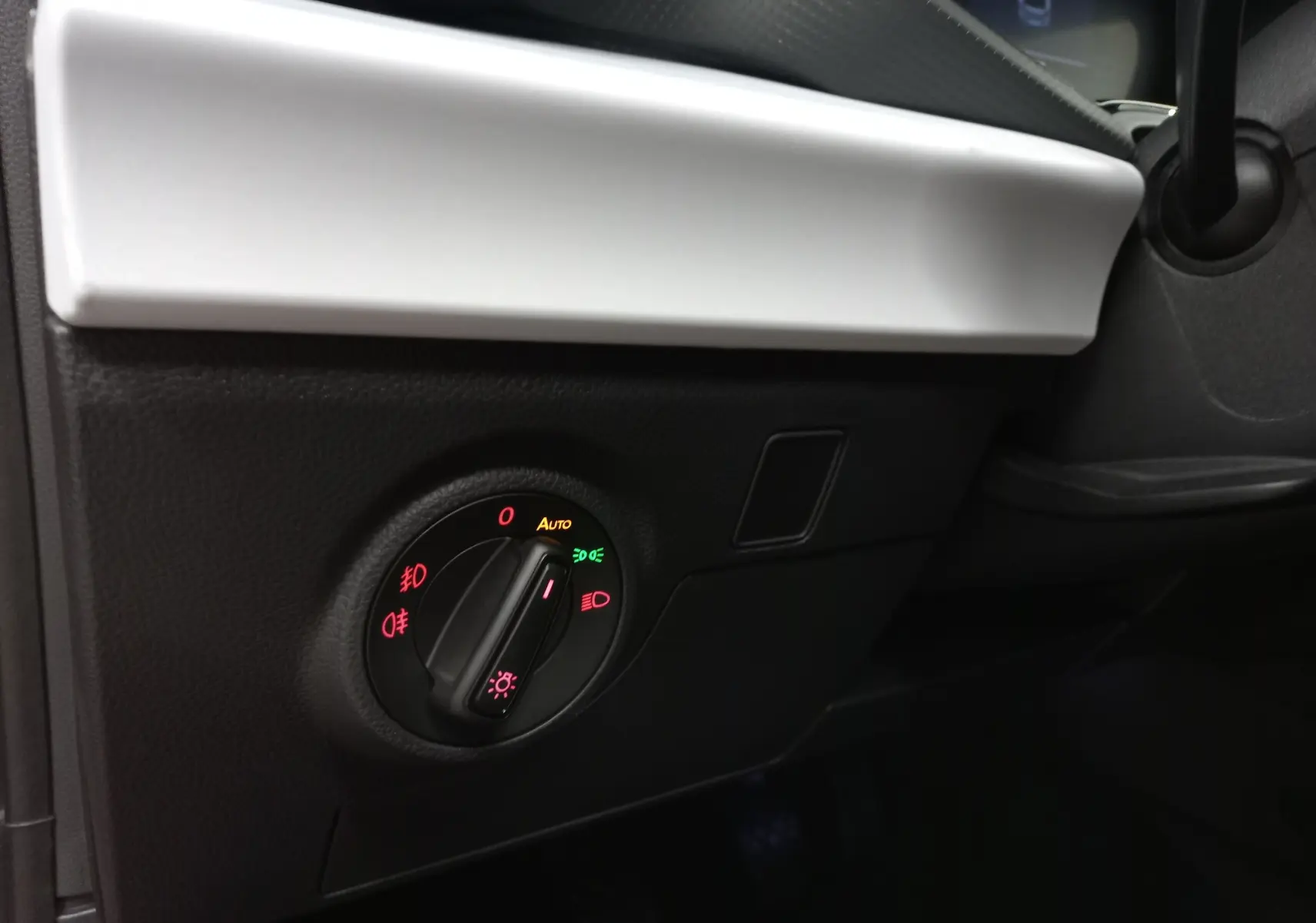 Gros plan sur le bouton de commande des phares dans l’habitacle noir et blanc d’une SEAT Ibiza Rouge Désir 2025.