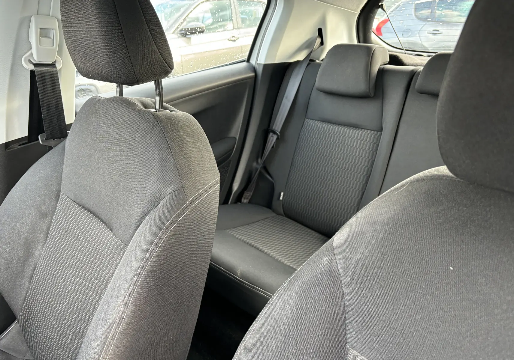 Intérieur noir en tissu de la Peugeot 208 1,6L HDI Active 2017, vue rapprochée des sièges avant et arrière.