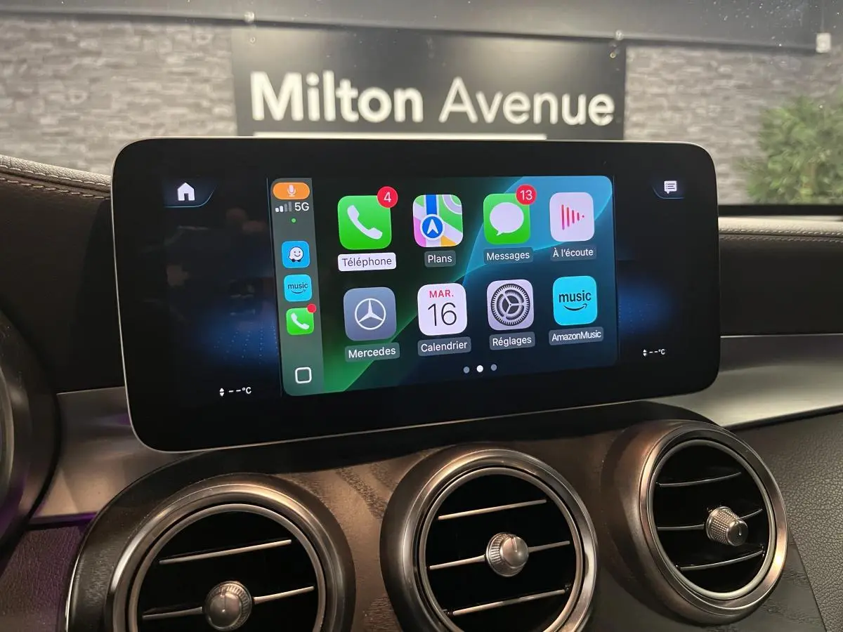 Écran central tactile avec Apple CarPlay dans l'habitacle d'une Mercedes GLC gris, vue rapprochée du tableau de bord.