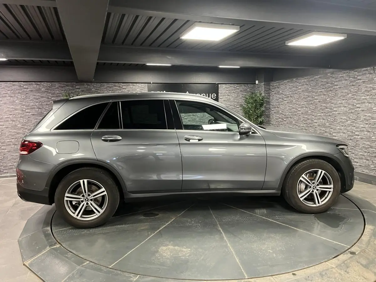 Profil côté gauche d'un Mercedes GLC gris métallisé 2019 en intérieur avec jantes alliage 5 branches.