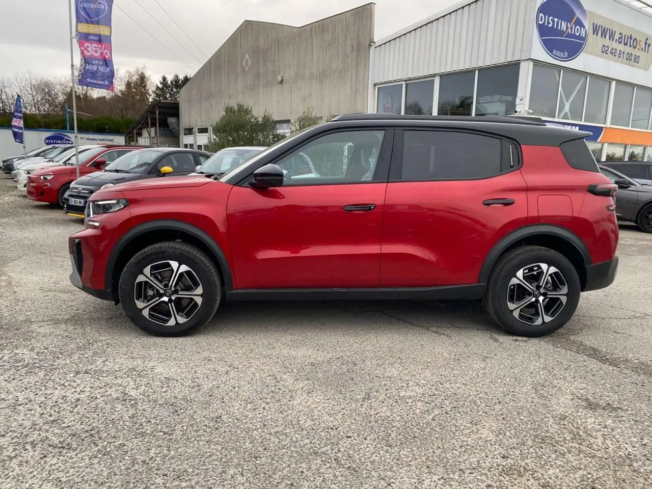 Profil côté gauche du Citroën C3 Aircross 2025 rouge Elixir avec toit noir et jantes alliage 17 pouces sur parking extérieur.