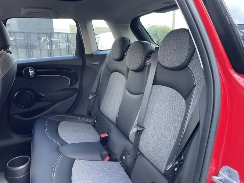 Vue intérieure arrière côté droit d'une MINI 5P rouge 2021, montrant les sièges arrière bi-matière gris et noir avec appuie-têtes ronds.