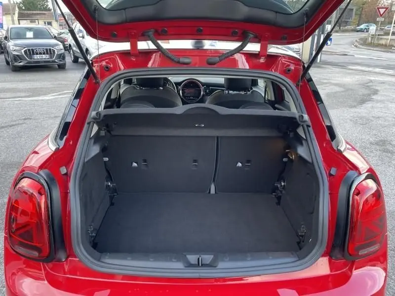 Coffre ouvert vu de l'arrière d'une MINI 5P Cooper D rouge, avec banquette arrière et tableau de bord visibles.