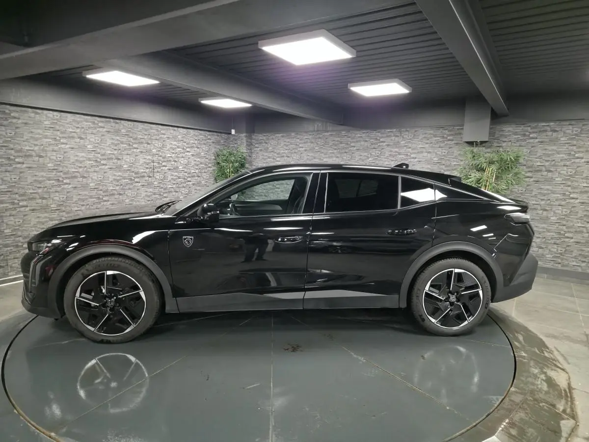 Peugeot 408 hybride noire vue de profil côté gauche, avec jantes alliage 19 pouces et toit plongeant.