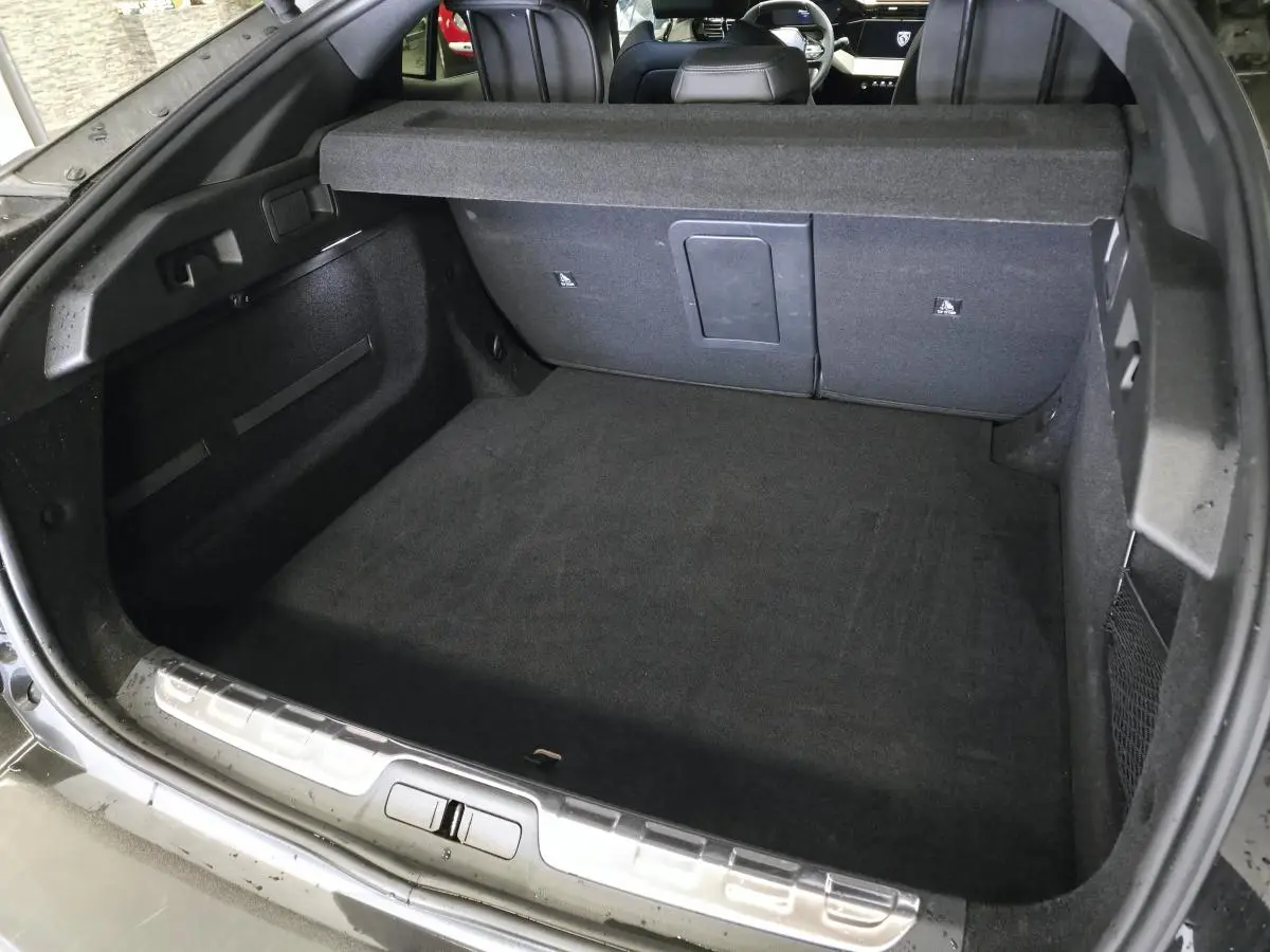 Coffre ouvert vu de l'arrière d'une Peugeot 408 noire, montrant un espace de chargement propre et spacieux.