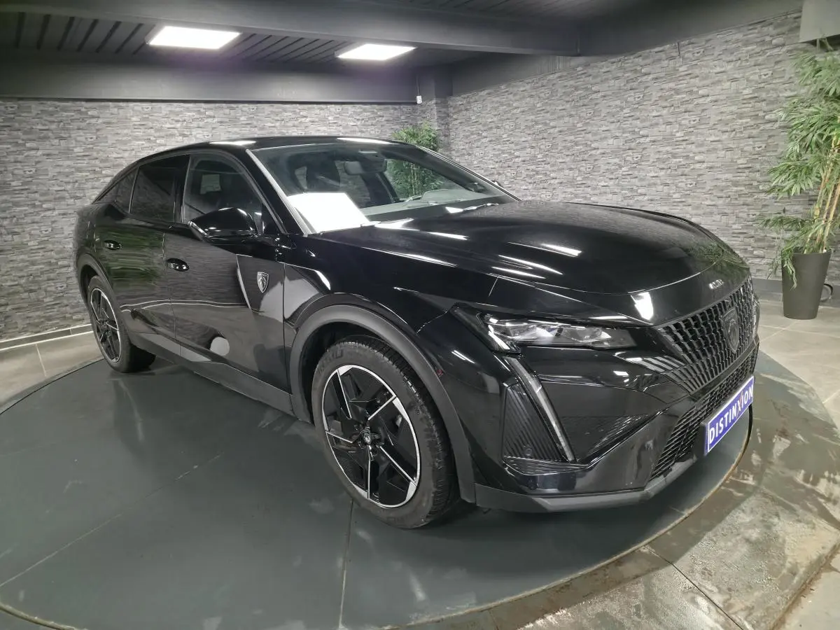 Peugeot 408 noire vue en 3/4 avant droit, avec calandre distinctive et jantes alliage 19 pouces diamantées.