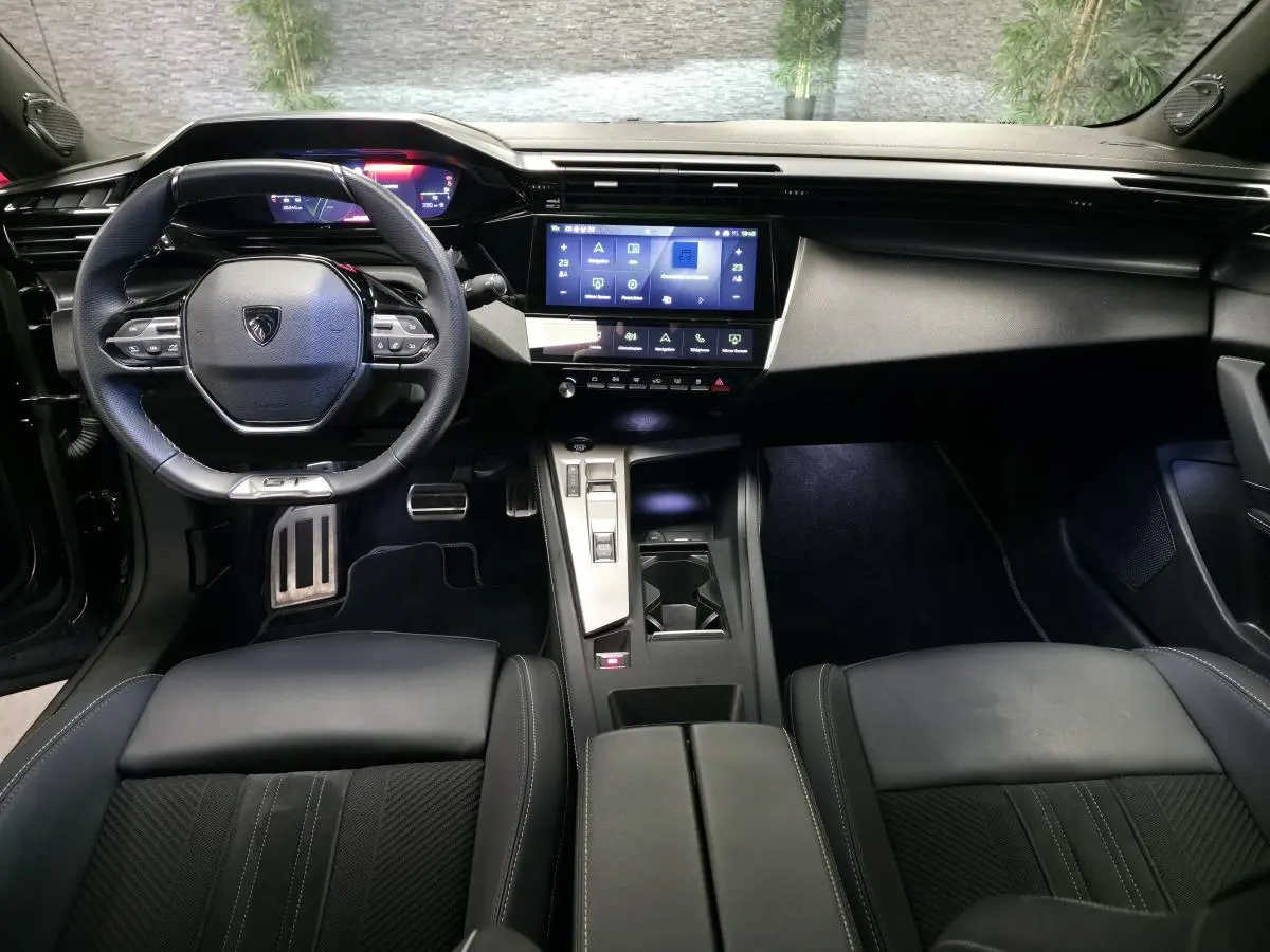 Vue intérieure avant du Peugeot 408 GT 2024 noir, avec volant cuir, écran tactile 10 pouces et console centrale moderne.